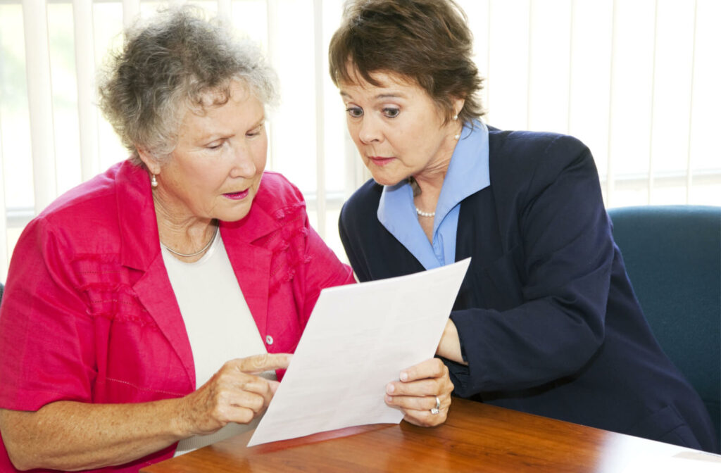 A senior woman and a professional-looking woman reviewing a document together.