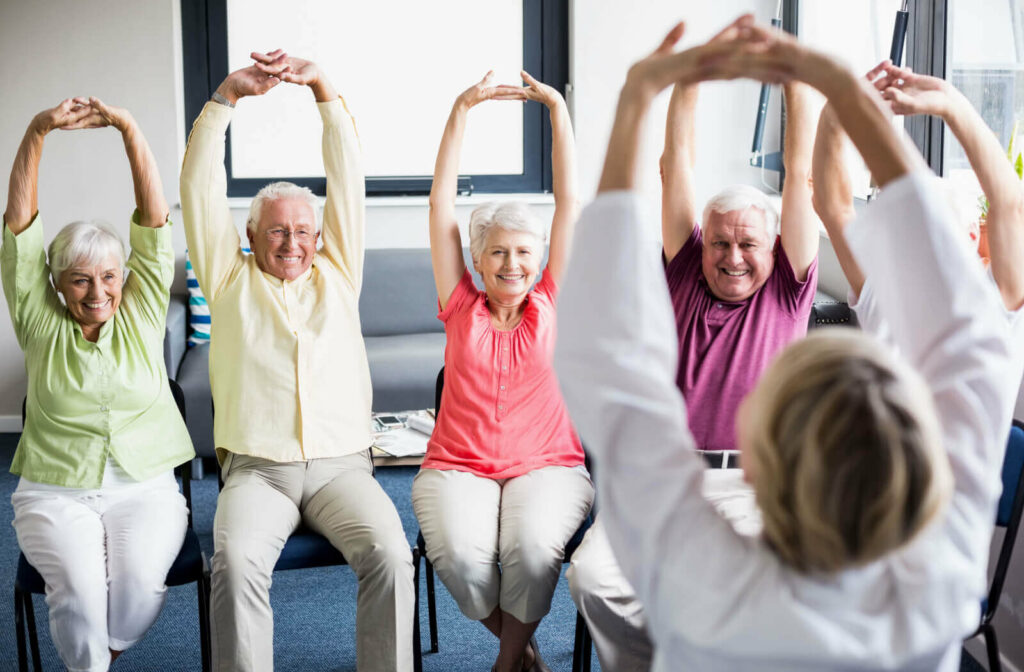 A group of seniors stretching while seated.