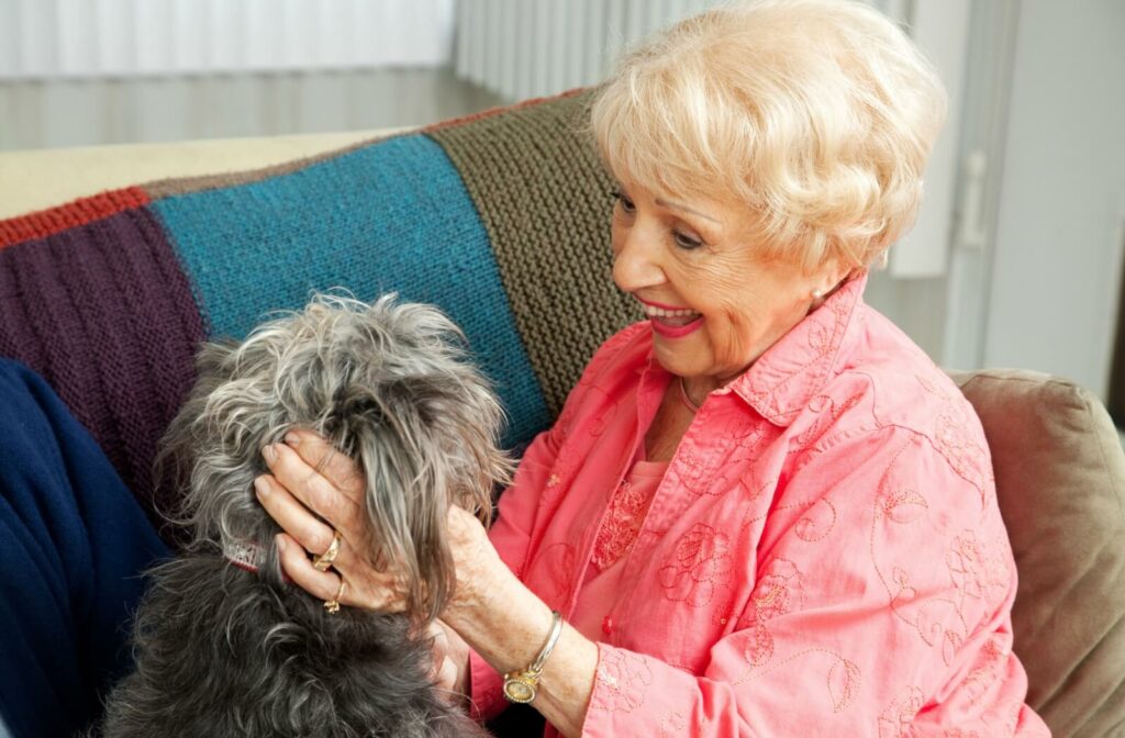 An older adult woman playing with a small dog in a living room